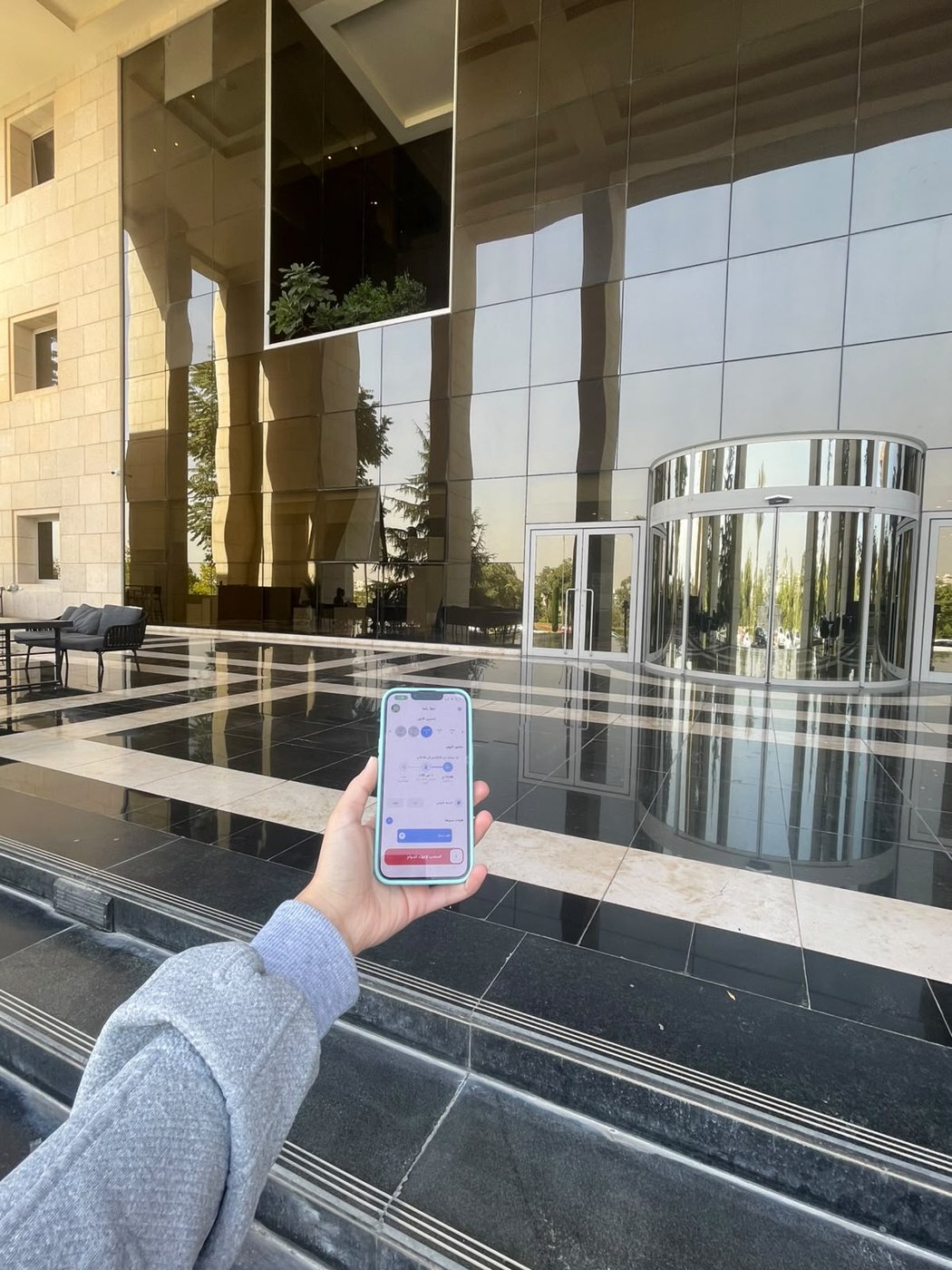 Dawami open on a phone outside a workplace, showing the geofenced attendance screen